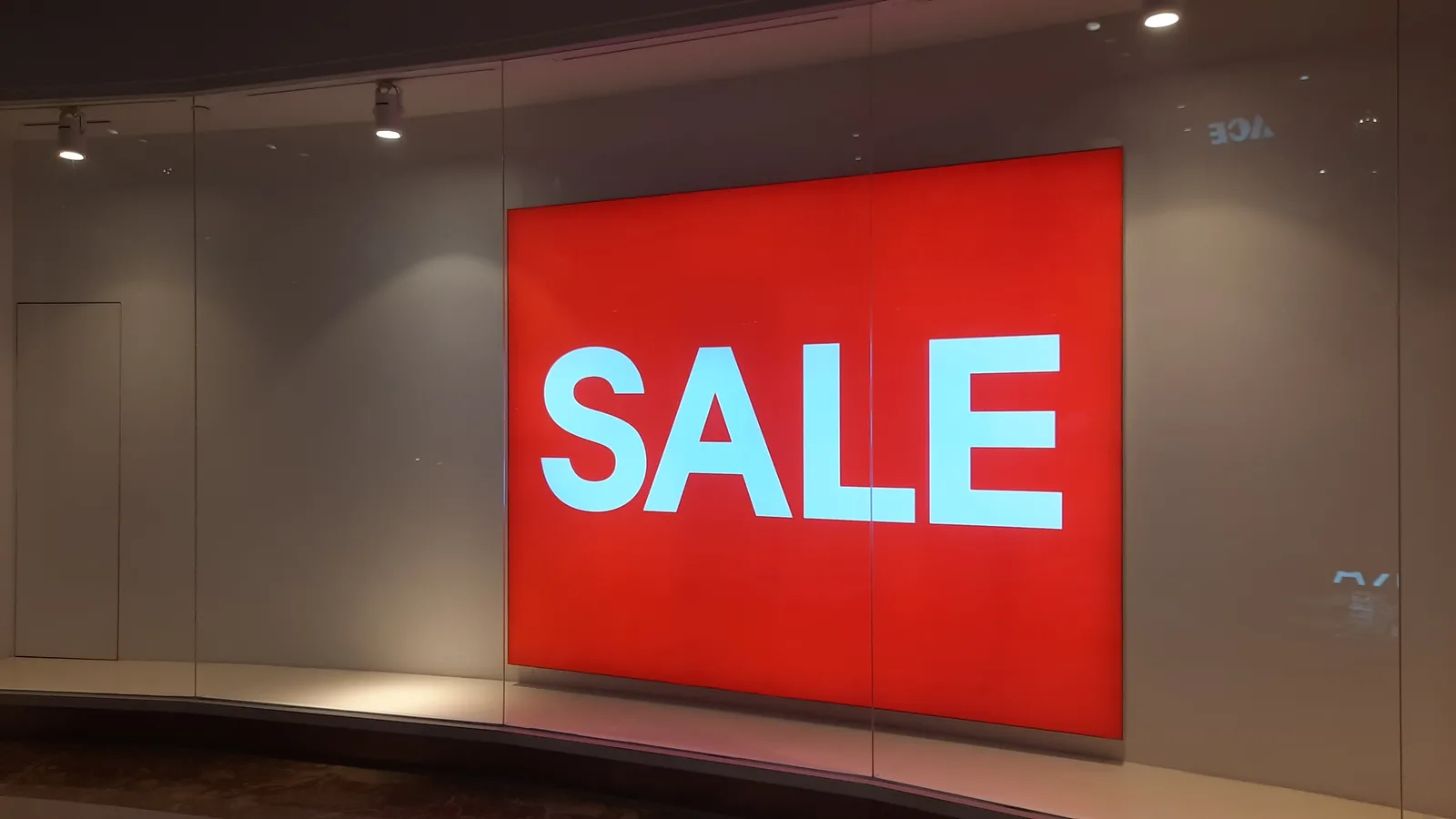 Bright red sale sign in storefront display in Jakarta mall, Indonesia.